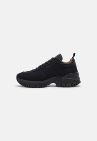 Czarne buty sportowe z tkaninową cholewką, gumową podeszwą, wyściełanym kołnierzem i sznurowadłami. Posiadają teksturowany wzór oraz pętelkę przy pięcie.
