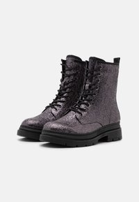 Bottines à lacets métalliques violettes avec une surface texturée, semelle noire contrastante et œillets robustes. Conçues pour la durabilité et le style.