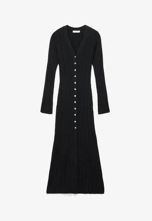 Črna, dolg rokav rebrasta pletena obleka z V-izrezom in osrednjo vrsto srebrnih gumbov, ki poteka od vrha do roba.
