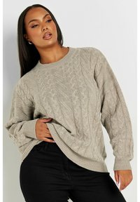 Jersey de punto trenzado en un color beige claro, con un clásico escote redondo y puños acanalados, de corte relajado y con un patrón texturizado.