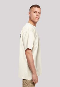 Cream short-sleeve t-shirt made of cotton, featuring a relaxed fit and visible stitching details. Simple design with no prominent patterns.