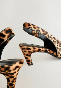 Des escarpins slingback en imprimé léopard, fabriqués en tissu texturé avec un accent en cuir noir ; dotés d'un talon effilé et de côtés ouverts.