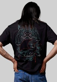 Schwarzes Baumwoll-T-Shirt mit auffälligen, bunten Grafiken von stilisierten Kreaturen auf der Rückseite, verziert mit filigranen Linienarbeiten und japanischen Textakzenten.