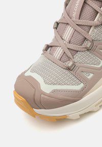 Lettvekts tursko med et pustende mesh-overdel i myk grå og lilac, forsterket tåhette og en teksturert gummisåle i tan.