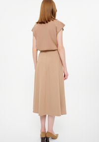 Beiges Kleid mit kurzen Ärmeln und taillierter Taille, das bis zur Midi-Länge fließt. Das Material wirkt glatt und hat minimale Nähte.