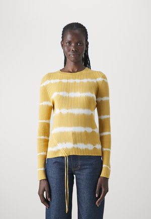Kollane ribikampsun valgete tie-dye triipudega. Omab ümardatud kaelust ja reguleeritavat ääret, kombineeritud tumesiniste teksadega.