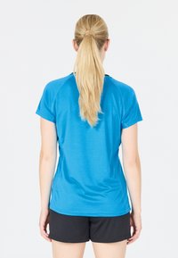 Blå atletisk t-shirt med korta ärmar och rund halsringning. Slät tyg med kontrasterande mörka detaljer vid halsringning och sidor.