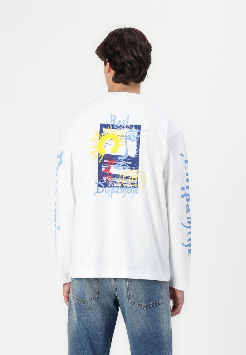 Tricou alb din bumbac cu mânecă lungă, prezentând un grafic colorat pe spate cu soare și designuri abstracte, inclusiv text albastru.