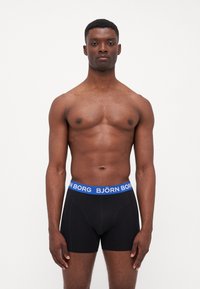 Schwarze Boxershorts mit einem blauen Bund, der den Markennamen "BJÖRN BORG" trägt. Der Stoff wirkt weich und elastisch.