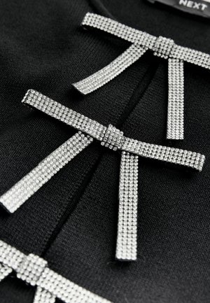 Schwarzes Kleidungsstück aus Stoff mit drei mit silbernen Strasssteinen besetzten Schleifen, die jeweils eine glatte Textur und ein flaches Design aufweisen.
