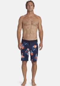 Pantaloni da bagno blu navy con motivo floreale arancione e blu, con una texture a rete e una vita con cordino nero.