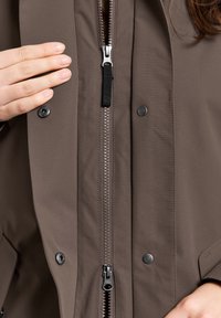 Bruine ritsjack met een gladde stof, met een centrale rits, drukknoopjes en verstelbare hardware accenten op de rits.