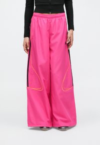 Rózsaszín, széles szárú nadrág könnyű anyagból, fekete oldalsávokkal és narancssárga varrási részletekkel. Rugalmas derékrész a kényelemért.