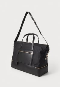 Sort taske med nylon krop og læderdetaljer, dobbelte top-håndtag, justerbar rem, frontlomme med lynlås og detaljer i gyldent metal.