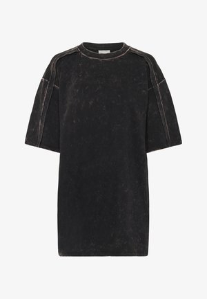 Camiseta negra de gran tamaño hecha de algodón texturizado, con tela suave y desgastada, mangas anchas y costuras de contraste.