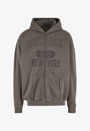 Pelēka kapuci jaka ar rāvējslēdzēju no mīksta auduma, ar kengura kabatu, ribveida aprocēm un uzkrītošu tekstu uz krūtīm: "KARL KANI 89 NEW YORK."