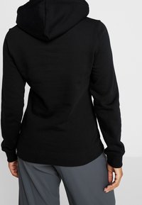 Felpa nera con cappuccio, maniche lunghe, orlo e polsini a coste. Il tessuto appare liscio con un design semplice e minimalista.