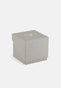 Grau strukturierter Kasten mit einem dreieckigen goldenen Logo an der Oberseite, das ein einzigartiges schräges Klappdesign und einen stabilen Boden aufweist.