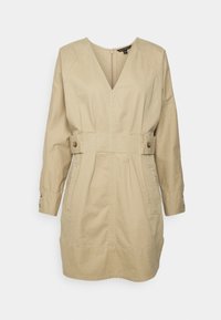 Robe beige à manches longues avec décolleté en V, détails de couture sur le devant, poches latérales, ceintures à boutons à la taille et fermeture éclair dans le dos.