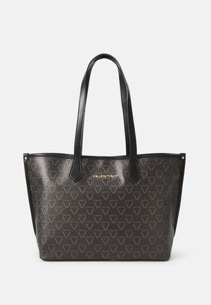 Saco tote em pele preta com um acabamento texturizado, padrão de logótipos geométricos e detalhes em dourado. Apresenta duas alças robustas para facilitar o transporte.