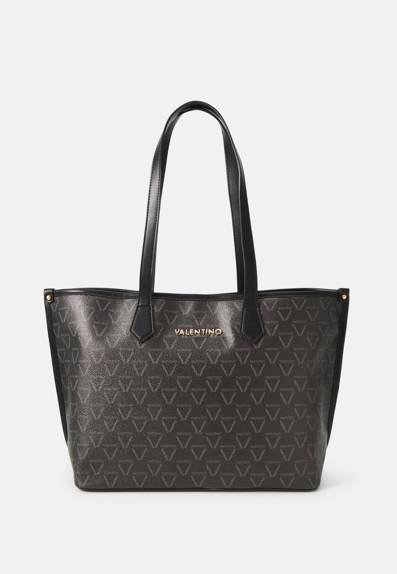 Saco tote em pele preta com um acabamento texturizado, padrão de logótipos geométricos e detalhes em dourado. Apresenta duas alças robustas para facilitar o transporte.