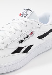 Weiße Ledersneaker mit schwarzen Akzenten und strukturiertem Sohlen. Verfügt über ein auffälliges Reebok-Logo, ein kanadisch inspiriertes Emblem auf der Zunge und flache Schnürsenkel.