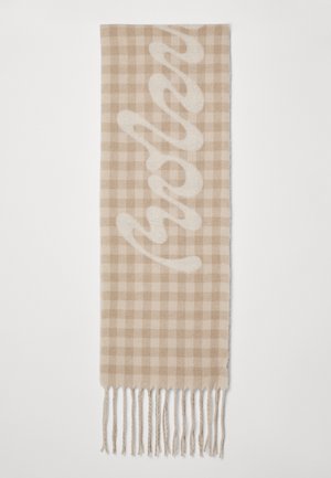 Vevet beige tørklæde med et ternet mønster og en blød tekstur, prydet med frynser i enderne og et styliseret tekstdesign.