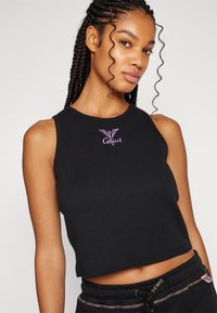 Top corto nero in cotone con scollatura rotonda e design senza maniche. Presenta un logo ricamato viola sul petto.