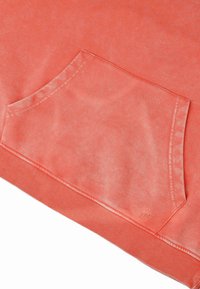Koraal sweatshirt met een voorzak, geribbelde zoom, zachte textuur en een subtiel vervagingseffect. Merknnaam gedrukt nabij de zoom.