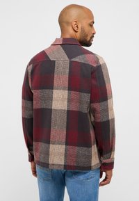 Kariertes Hemd in Rot, Beige und Dunkelgrau. Mit spitzem Kragen, langen Ärmeln und Knopfmanschetten. Strukturierter Stoff mit Karomuster.