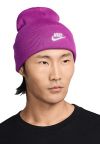 Berretto di lana viola con texture a coste e logo Nike bianco davanti. Indossato da una persona con una maglietta nera.
