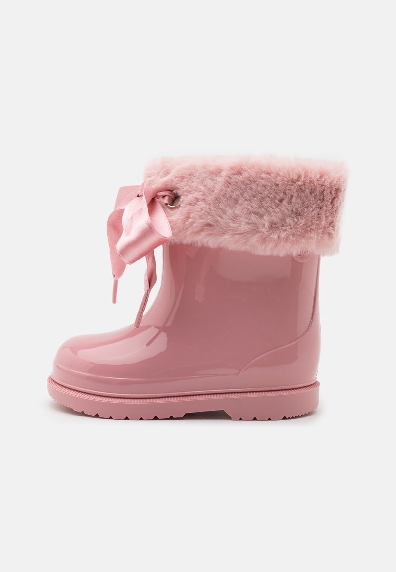 Botte de pluie imperméable rose avec un matériau glossy, un revers en fourrure douce, un lien en satin et une semelle en caoutchouc texturé pour l'adhérence.