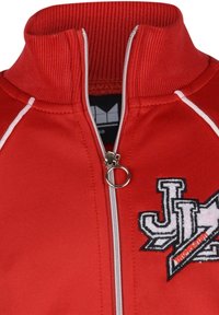Červená zipová bunda vyrobená z hladkého materiálu, s vroubkovaným límcem a bílými akcenty, zdobená vyšitým logem a stříbrným zatahovákem.
