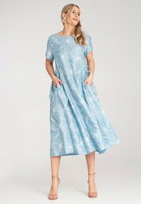 Jasnoniebieska, kwiecista sukienka midi z krótkimi rękawami, z wysmukloną talią, bocznymi kieszeniami oraz białymi wzorami liści, wykonana z miękkiego, lekkiego materiału.