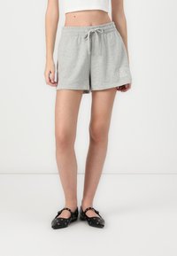 Grye bomullsshorts med elastisk midje og snøring, med en hvit "GAP"-logo på venstre ben. Kombinert med svarte leiligheter.