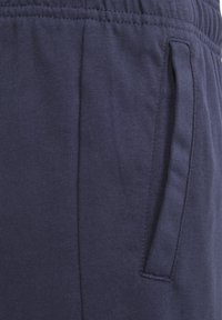 Navy blue sweatpants made of soft cotton blend, featuring an elastic waistband, side pockets, and a ribbed texture.