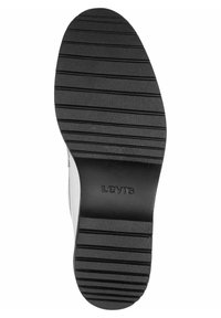 Svart gummisåle med horisontale spor og teksturert overflate. Har "Levi's"-logoen preget på siden.