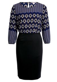Blusa a maniche lunghe in tessuto blu a motivi con polsini elasticizzati, abbinata a una gonna nera a tubino aderente. Chiusura a occhio di bue sul retro.