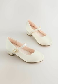 Pantofi Mary Jane din piele ecologică albă, cu vârf rotund, toc mic și o curea decorativă cu accent de nasture auriu.