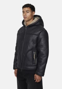 Giacca nera in pelle con cappuccio, dalla superficie texturizzata, cappuccio foderato in shearling, chiusura frontale con zip e tasche laterali, in una vestibilità casual.