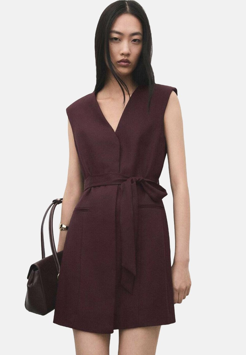 Bordowa sukienka bez rękawów z głębokim dekoltem w serek, paskiem w talii, bocznymi kieszeniami i strukturalnym krojem, wykonana z gładkiej tkaniny.