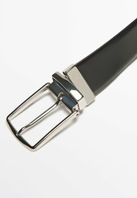 Schwarzer Ledergürtel mit einer silbernen rechteckigen Schnalle und einer Schlaufe. Der Riemen ist glatt mit einer polierten Oberfläche. Die Schnalle hat ein minimalistisches Design.