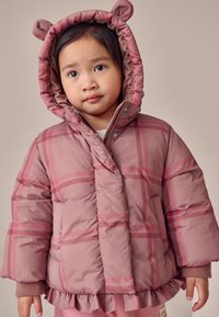 Giacca a piumino rosa tenue con motivo a quadri, dotata di cappuccio con orecchie da orso e orlo arricciato. Tessuto liscio imbottito, chiusura con bottoni.