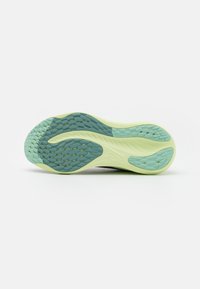 Suela de zapato de goma con una base verde claro, con patrones de tracción texturizados en azul oscuro y un acabado suave para mejorar el agarre.