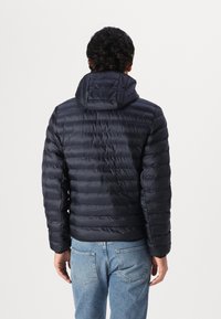 Marineblauwe pufferjack met capuchon, voorzien van een horizontaal gestikt ontwerp, elastische boorden en een glad, glanzend oppervlak. Casual pasvorm met een rechte zoom.