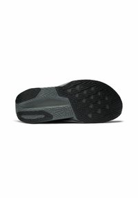 Schwarze Sportschuhsohle mit einem strukturierten Griffmuster, das dreieckige Formen aufweist, und einem glatten, grauen Akzent in der Mitte.