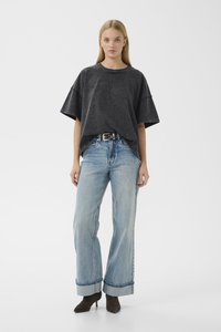 Overdimensjonert svart bomulls T-skjorte med oppbrettede korte ermer, kombinert med lyseblå vide denimjeans med rullet hem og svart belte.