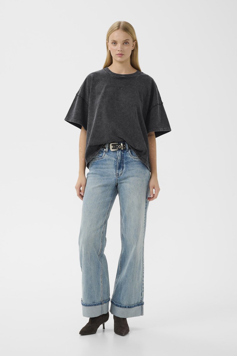 Overdimensioneret sort bomulds T-shirt med opsmøgede korte ærmer, parret med lyseblå brede denimbukser med opsmøg i kanten og sort bæltet.