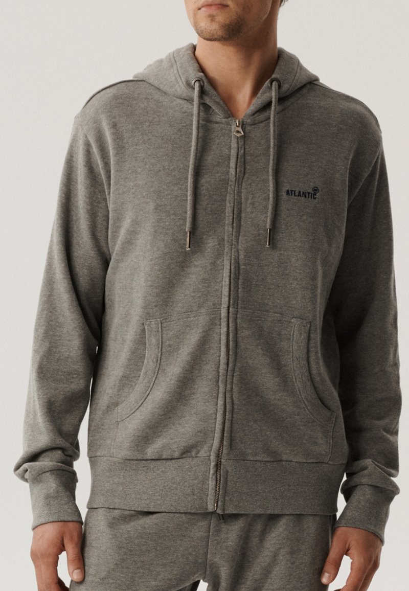 Szara bluza z kapturem na zamek, wykonana z miękkiego materiału. Posiada regulowany kaptur, kieszenie z przodu oraz małe logo na piersi. Regularny krój i długie rękawy.