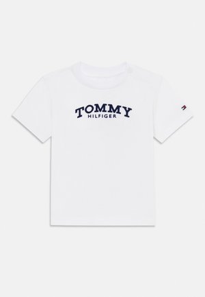 Camiseta blanca de manga corta para niño pequeño con texto "TOMMY HILFIGER" en azul marino en el pecho y pequeño logo de Tommy en la manga izquierda.